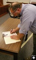 Tony Berget signs oath. Photo by Kootenai Valley Record.